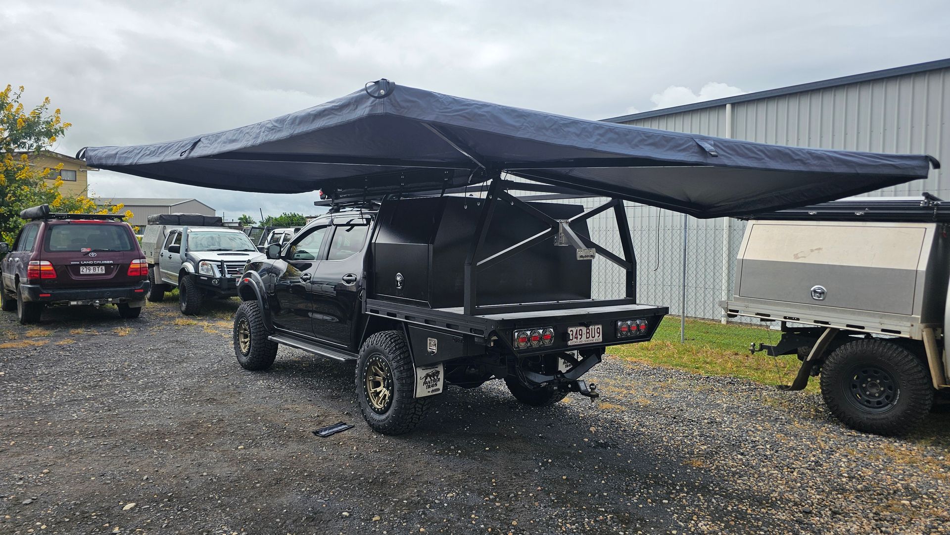Black pickup truck with an extended awning set up in a gravel lot on a cloudy day — Track N Back 4x4 In Mareeba, QLD