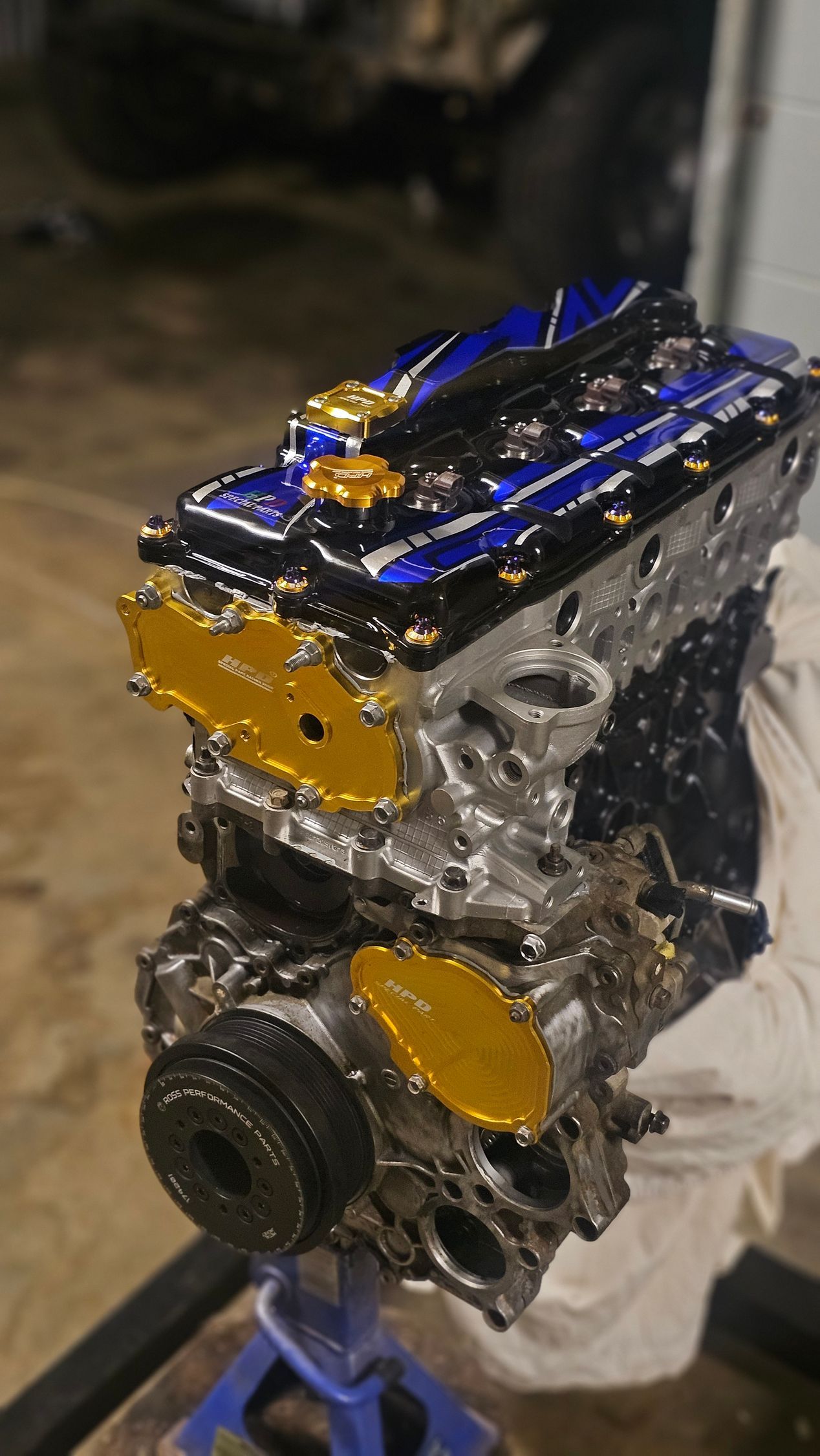 Engine with blue and gold valve covers, on a stand, in a garage — Track N Back 4x4 In Mareeba, QLD