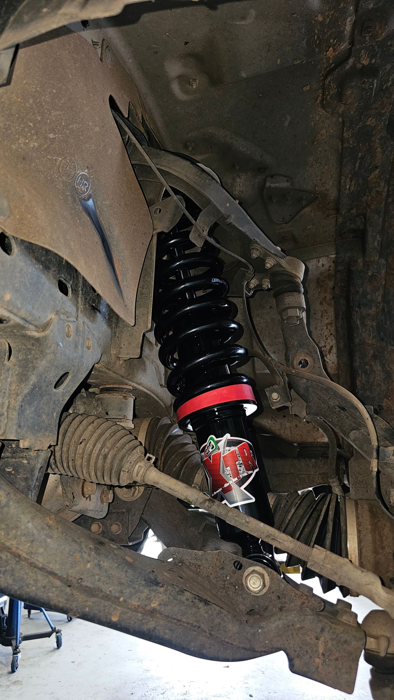 Black and red coilover shock absorber installed on a car's suspension, visible from below  — Track N Back 4x4 In Mareeba, QLD