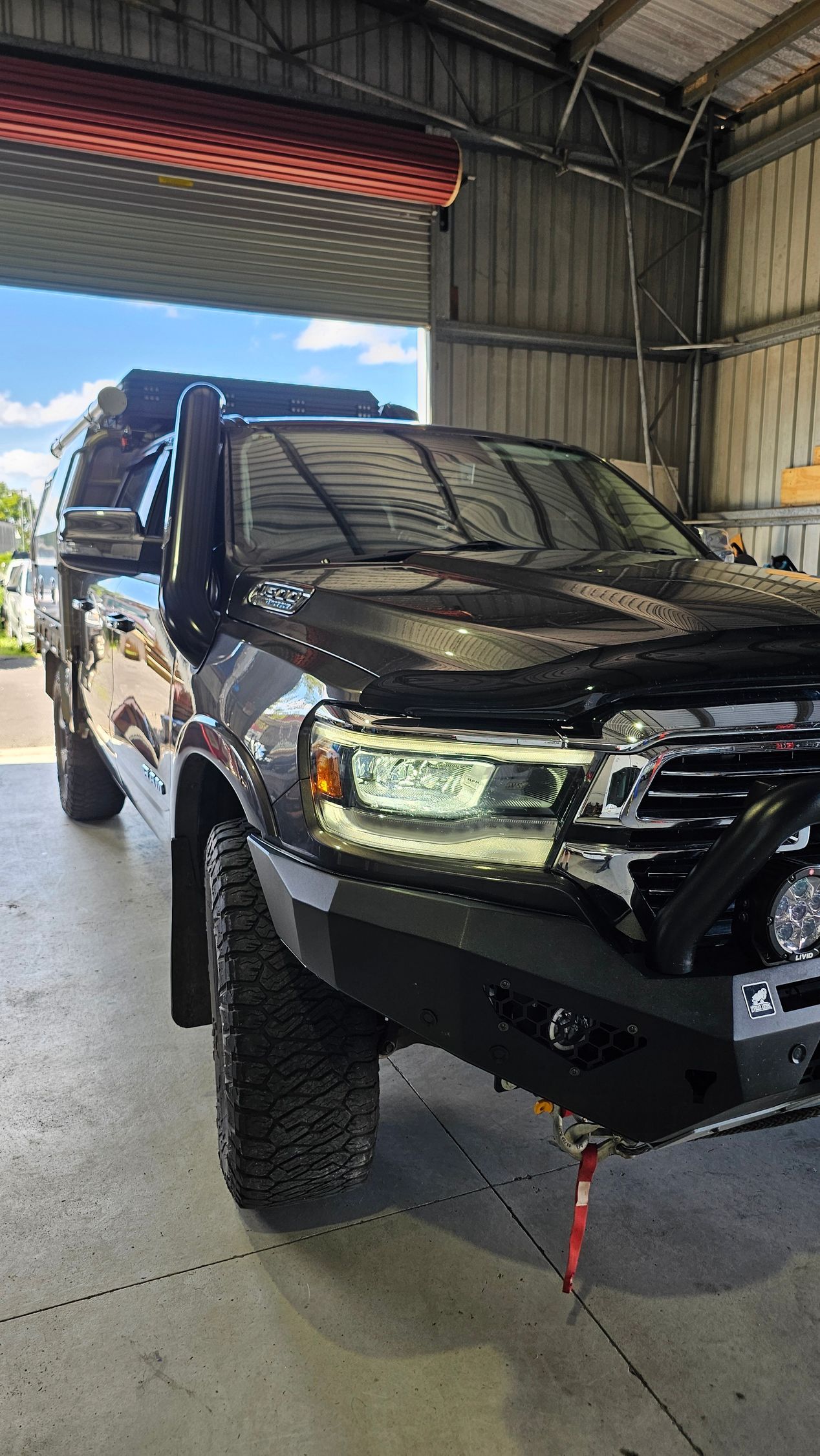 Black SUV with snorkel, off-road bumper, and large tires, parked inside a garage.