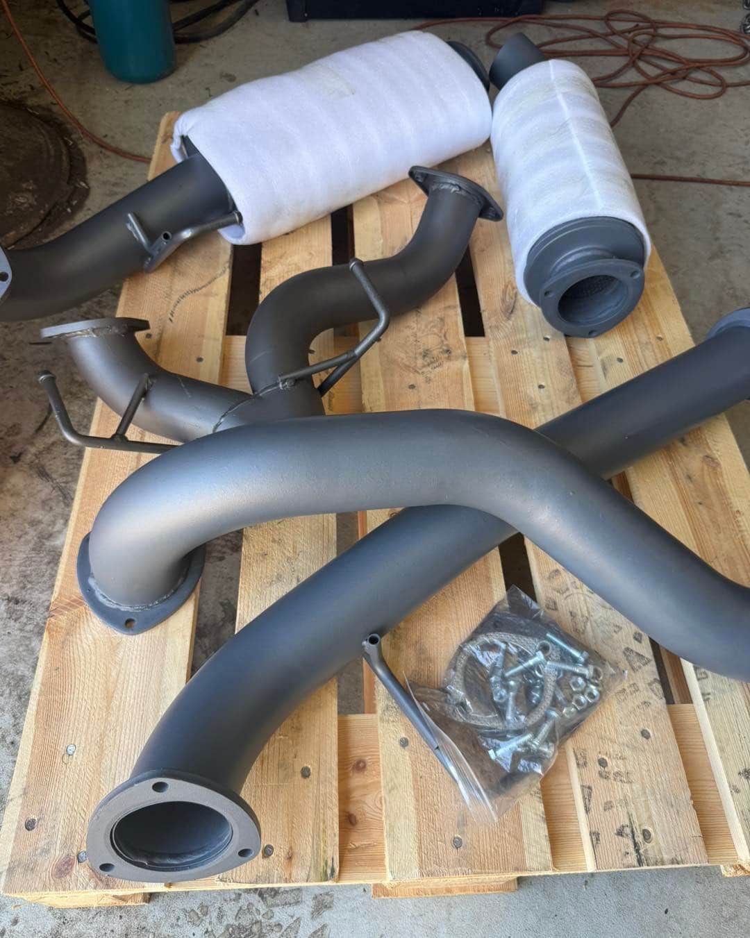 Black Exhaust Pipes and Mufflers on a Wooden Pallet — Track N Back 4x4 In Thursday Island, QLD