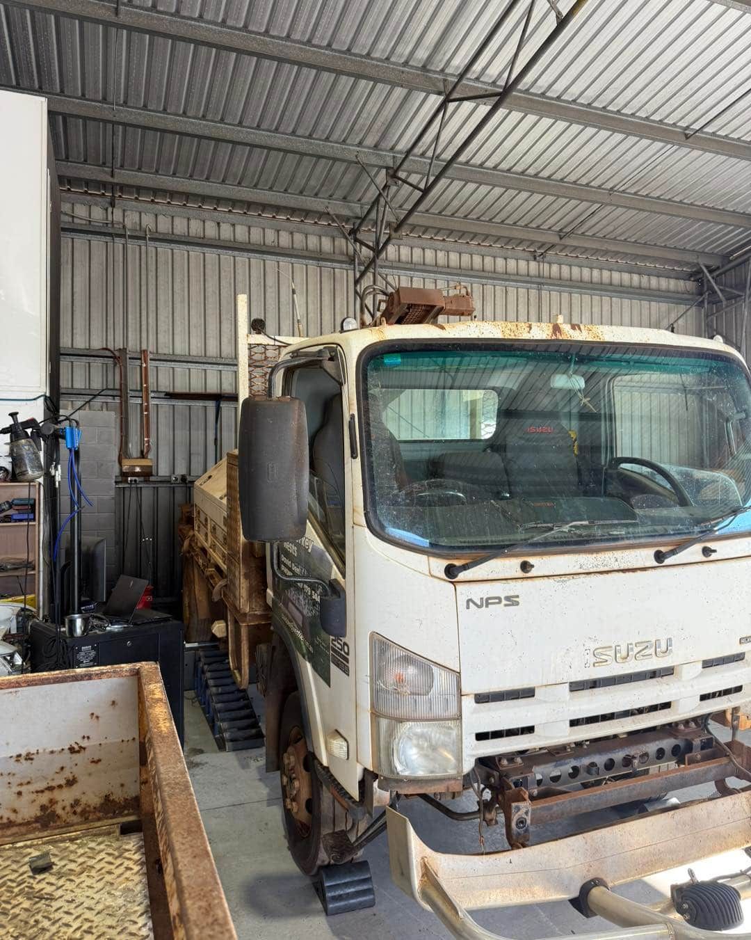 White Isuzu NPR truck in a Workshop, Rusty Bed, Weathered Appearance — Track N Back 4x4 In Mt Isa, QLD