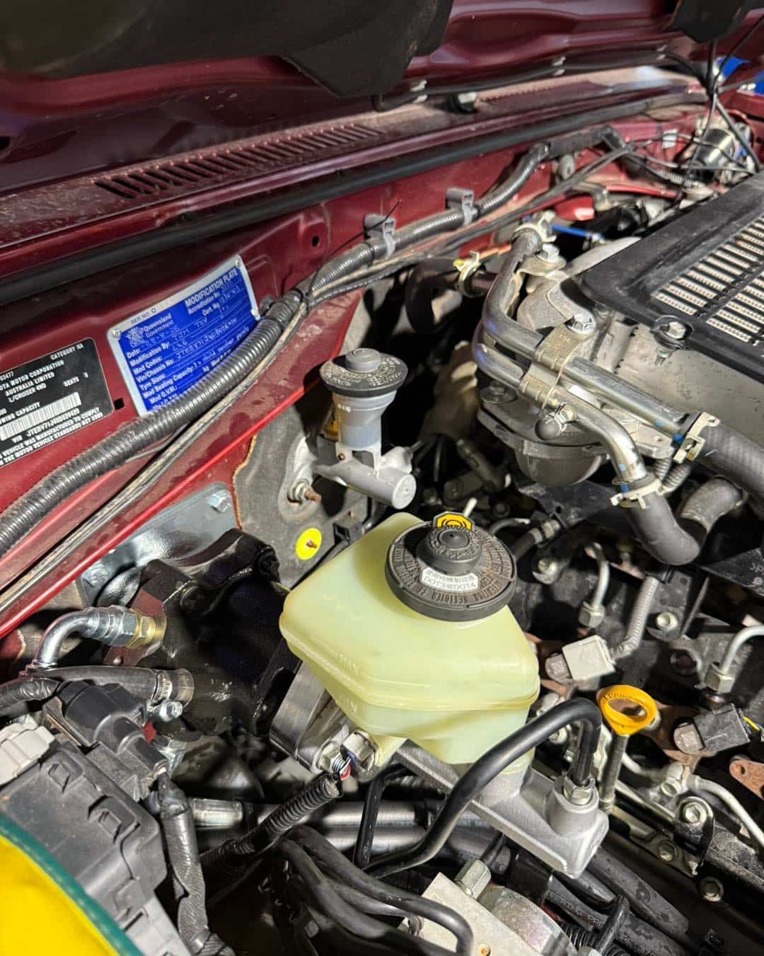 Engine Bay of a Red Car, Showing the Brake Master Cylinder and Fluid Reservoir — Track N Back 4x4 In Atherton, QLD