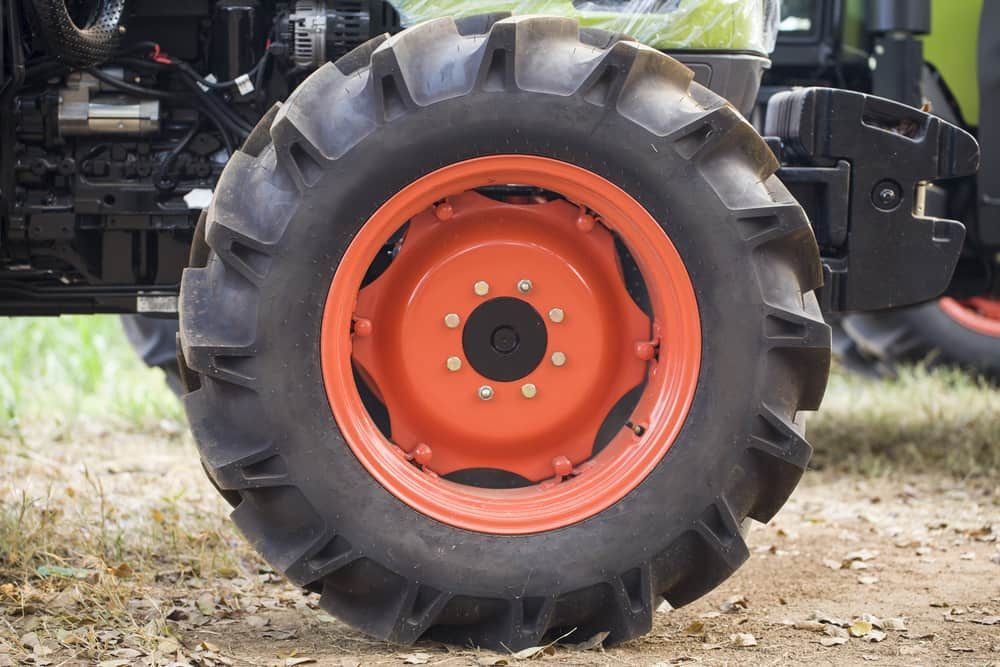 Tractor Wheel With Orange Rim and Black, Rugged Tire on a Farm — Track N Back 4x4 In Weipa, QLD