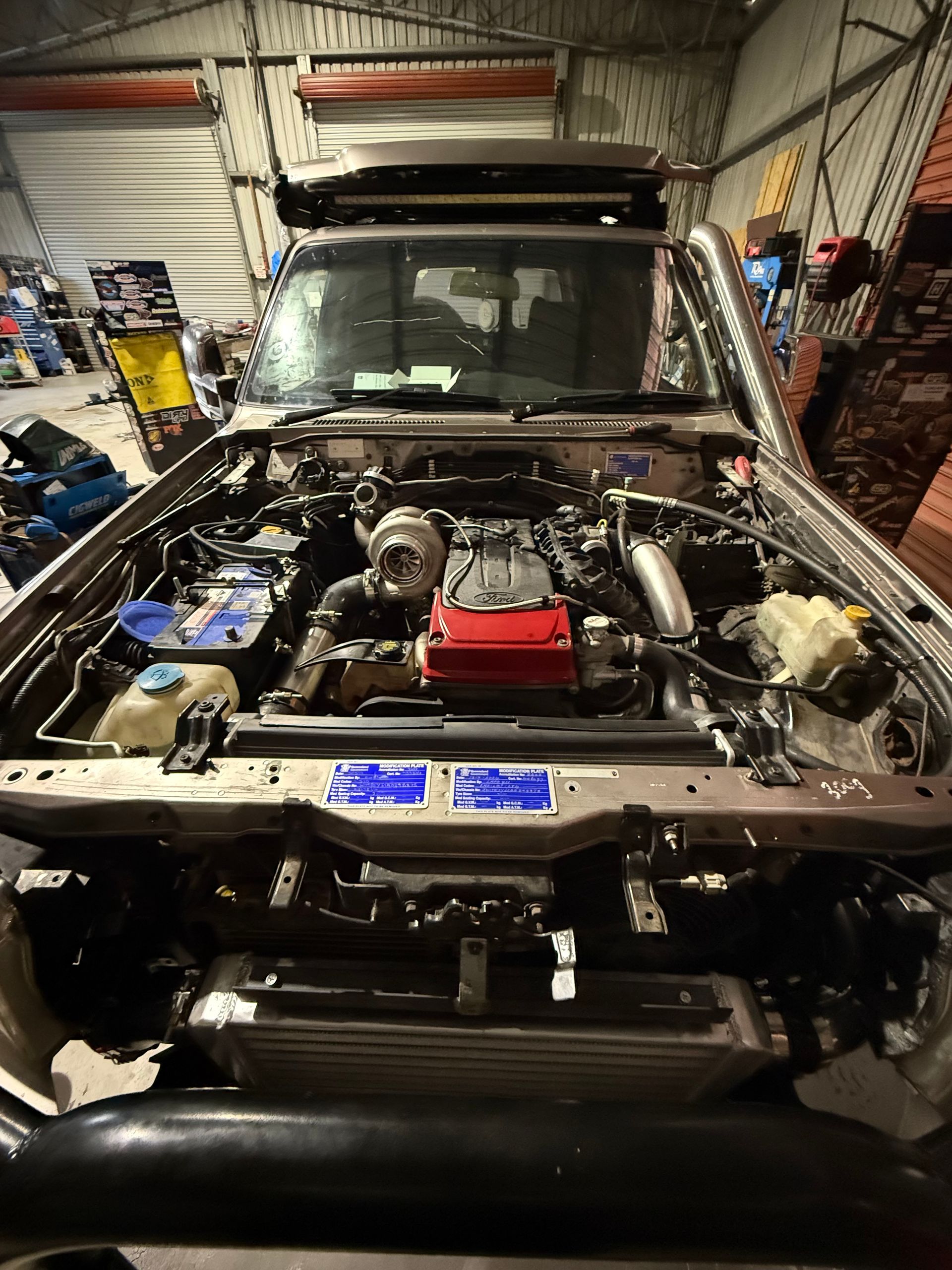 A modified engine bay of a car, with visible turbocharger and intercooler; indoors in a garage — Track N Back 4x4 In Mareeba, QLD