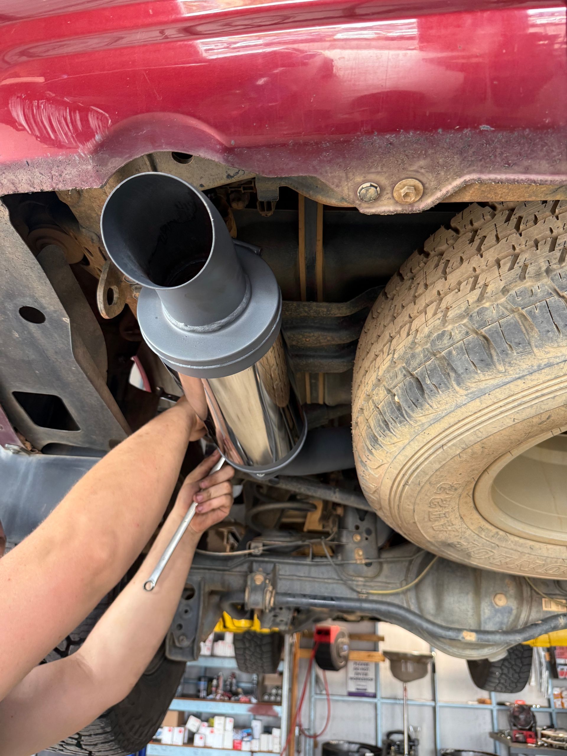 A Black Off-road Tire With a Bronze Wheel, Stacked Near Boxes — Track N Back 4x4 In Mareeba, QLD