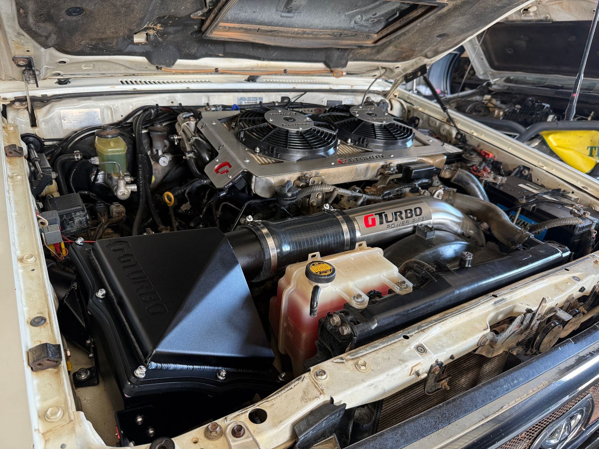 Car Engine Bay With a Black Battery, Red Positive Terminal Cover — Track N Back 4x4 In Mareeba, QLD