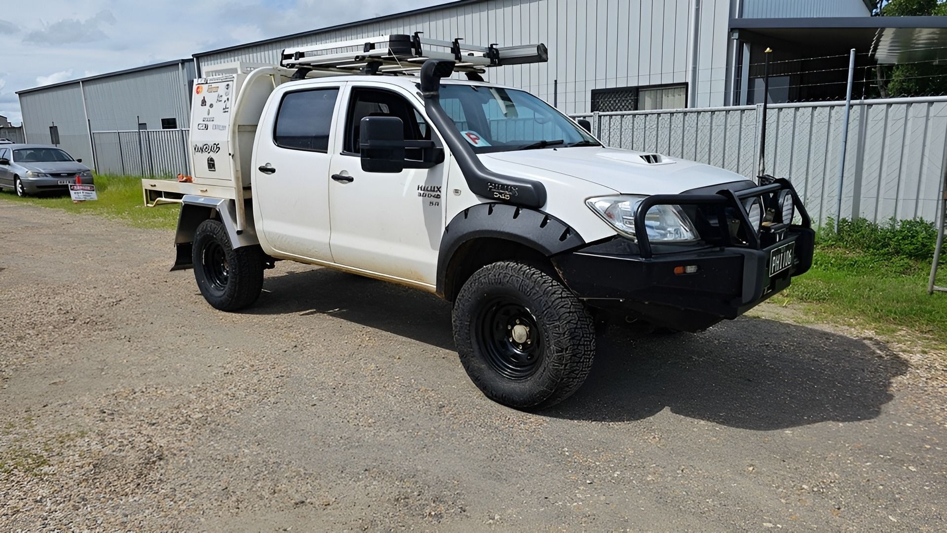 A Black Off-road Tire With a Bronze Wheel, Stacked Near Boxes — Track N Back 4x4 In Mareeba, QLD