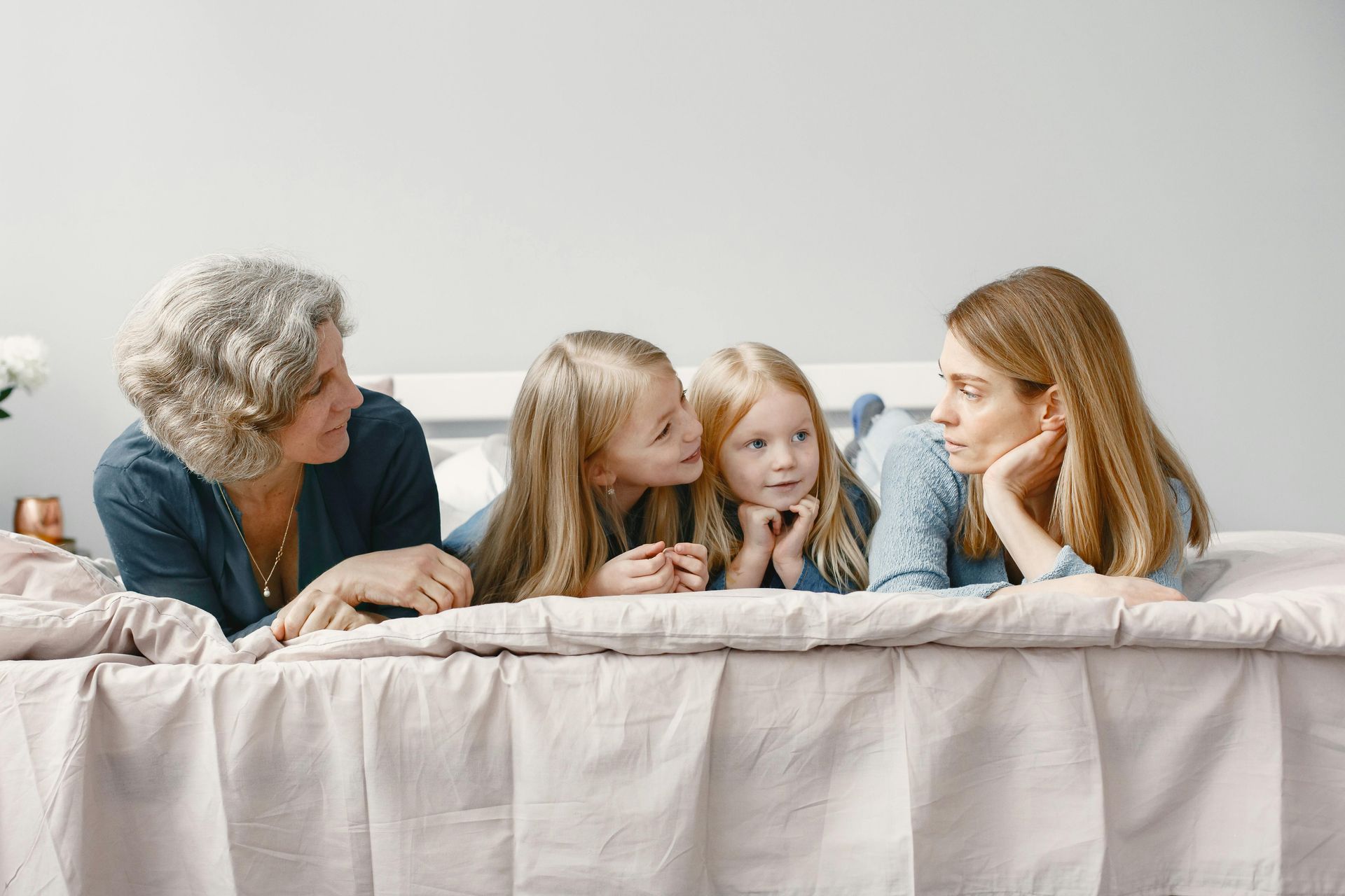 A group of women are laying on a bed talking to each other.