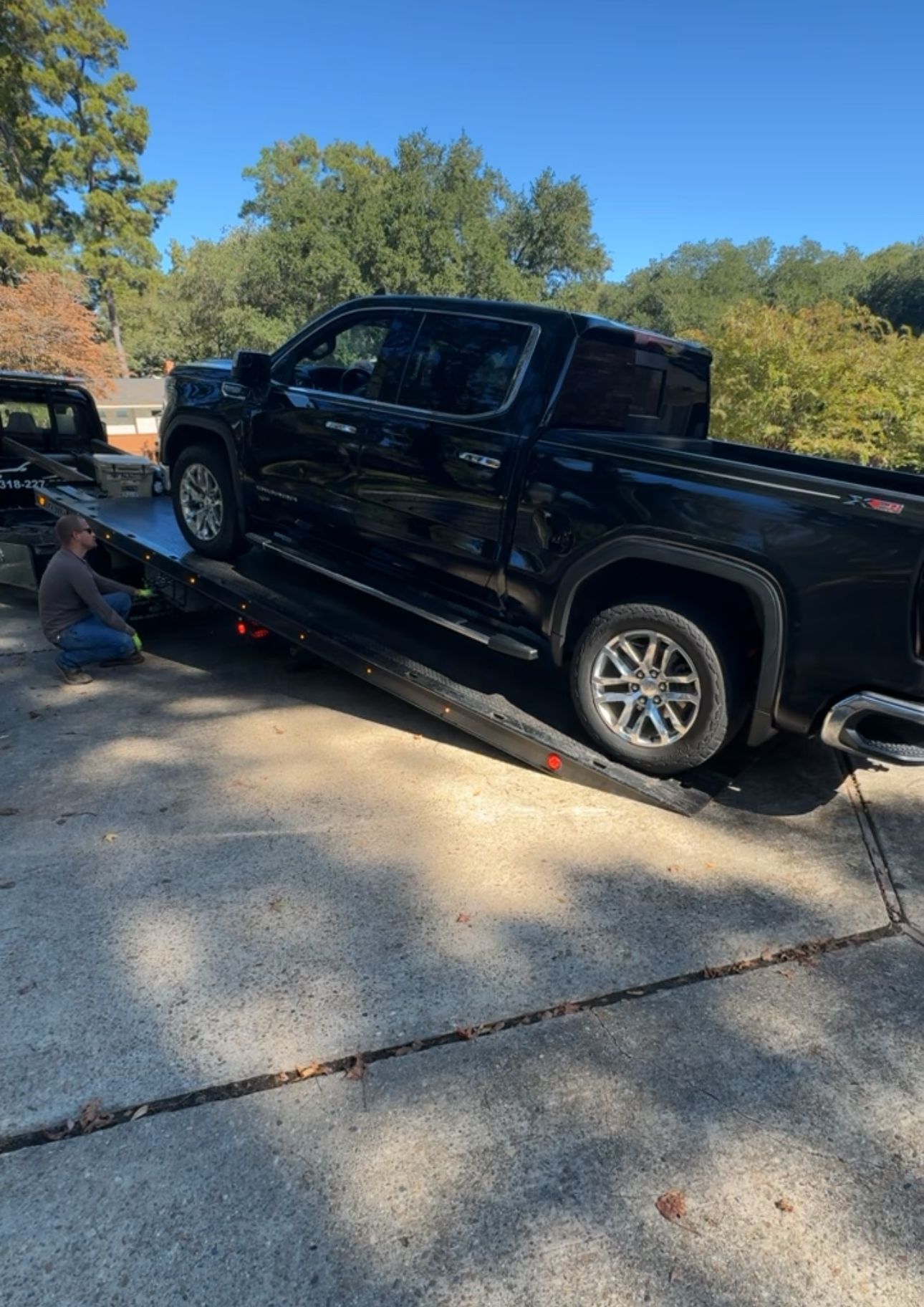 A black truck is being towed down a ramp by a tow truck.