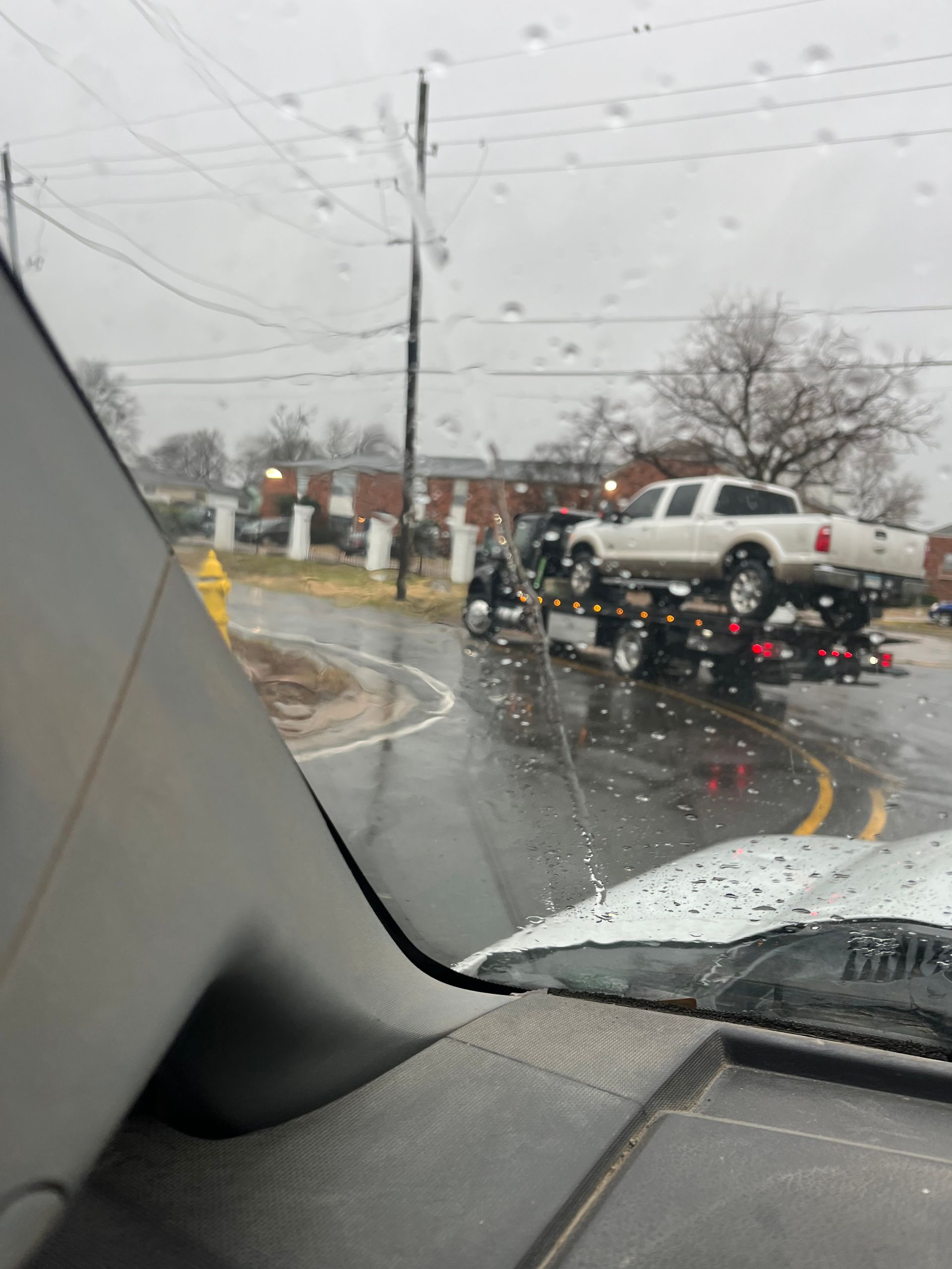 A white truck is being towed by a tow truck