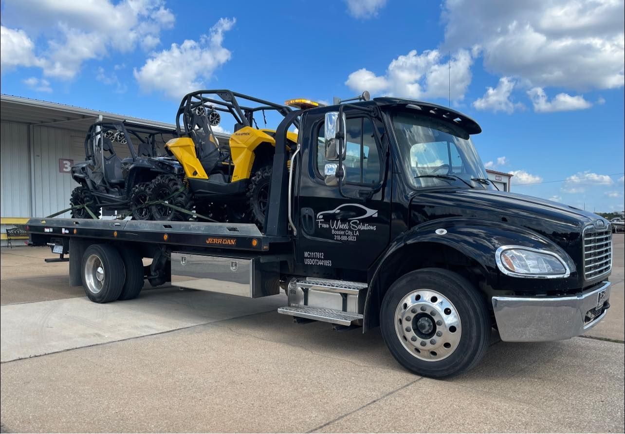A black tow truck is carrying a yellow and black atv.