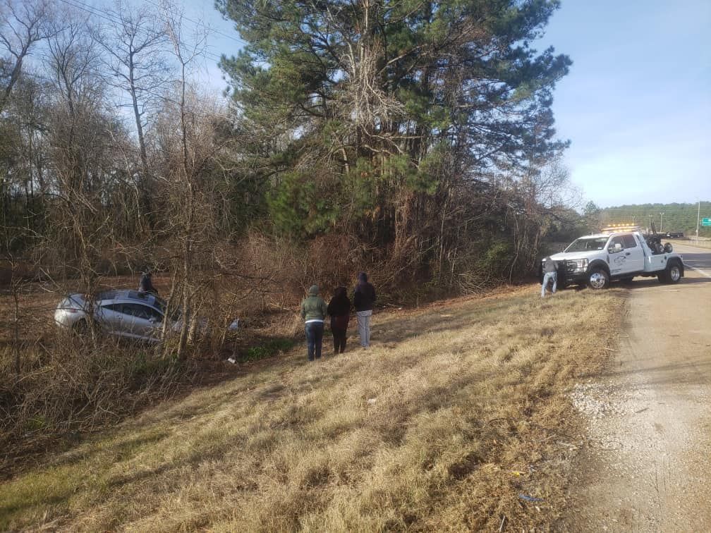 A tow truck is towing a car that has crashed into a tree.