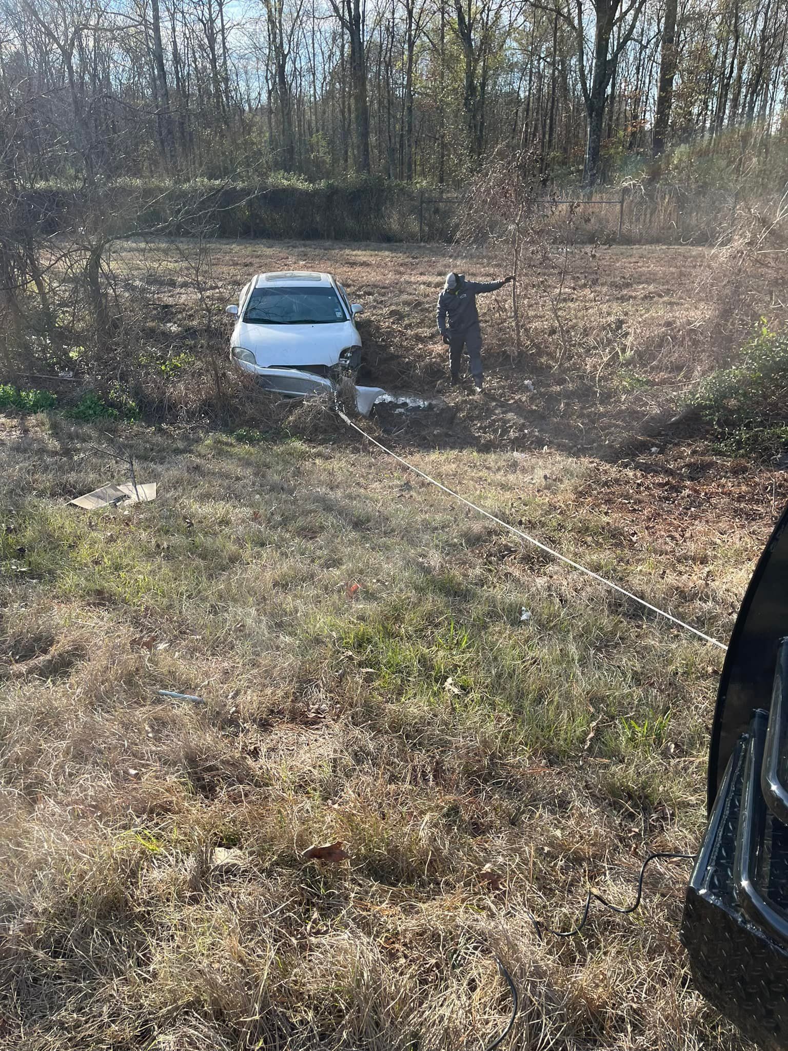 A man is standing next to a white car in a field.