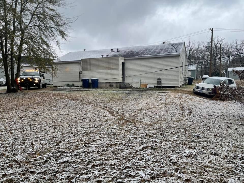 A truck is parked in front of a house in the snow.