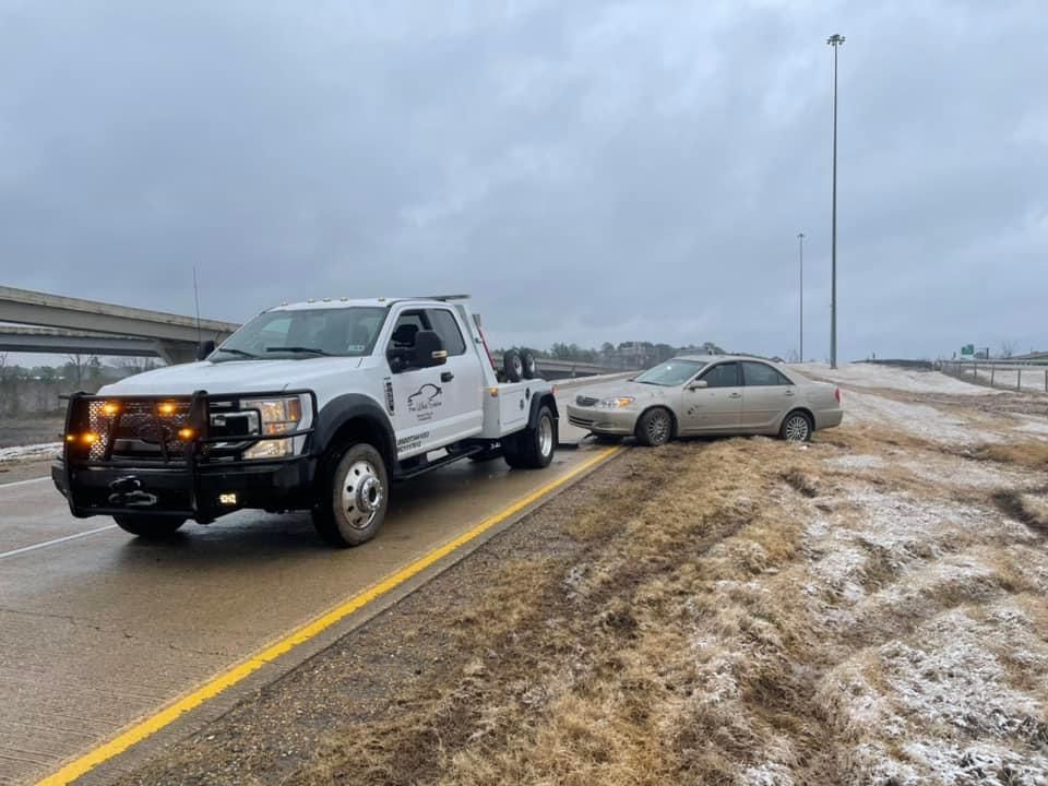 A tow truck is towing a car on the side of the road.