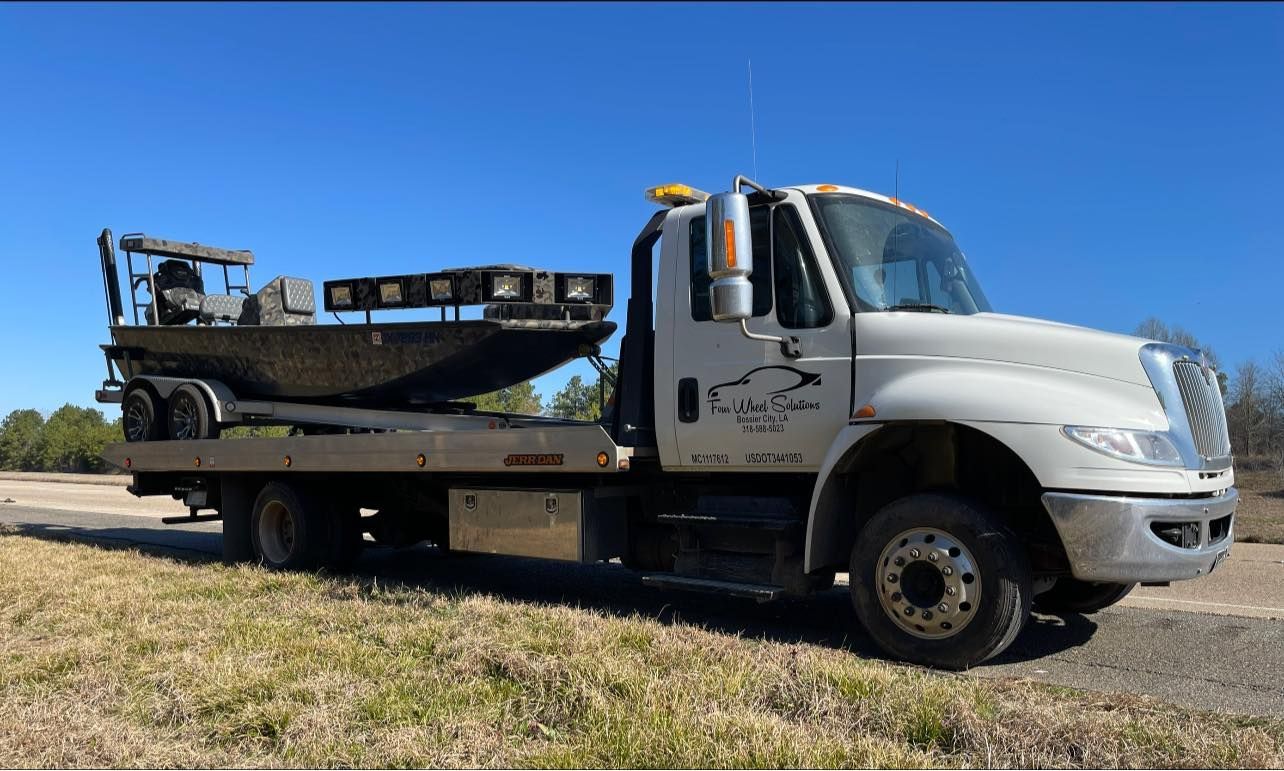 A tow truck with a boat on the back of it