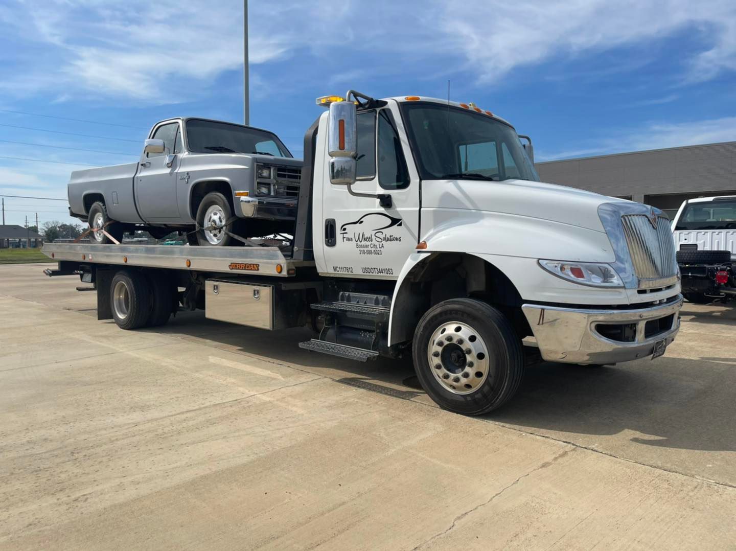 A tow truck with two trucks on the back of it.