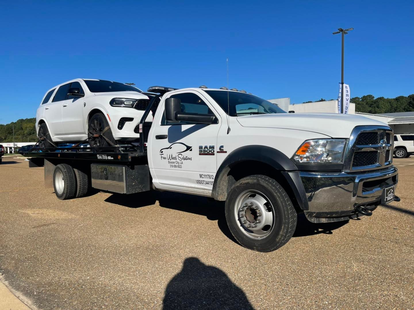 A white tow truck with a white car on the back of it.