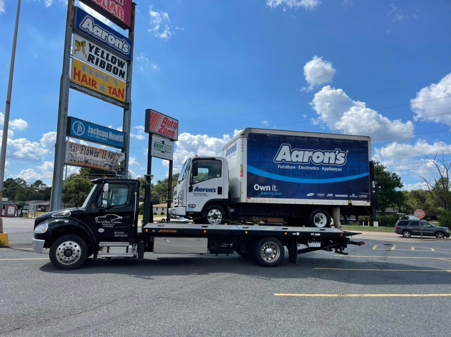 A tow truck is carrying a box on the back of it.