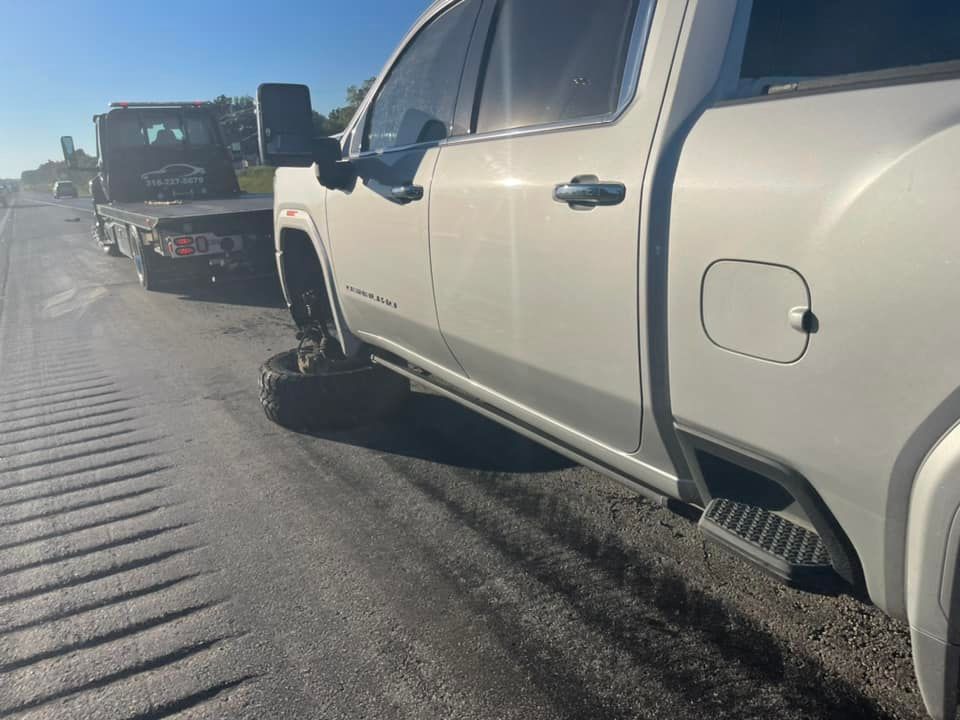 A white truck is parked on the side of the road next to a tow truck.