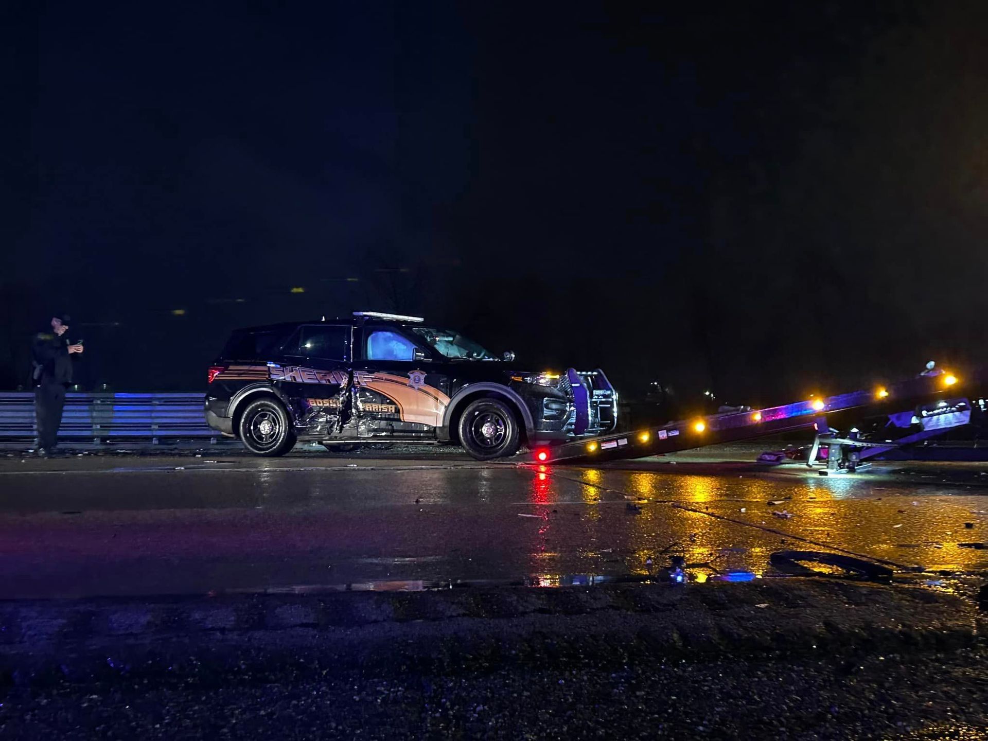 A police car is parked on the side of the road at night.