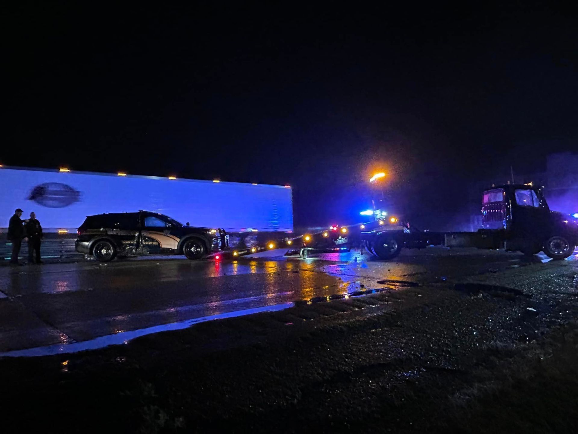 A truck is being towed by a tow truck at night