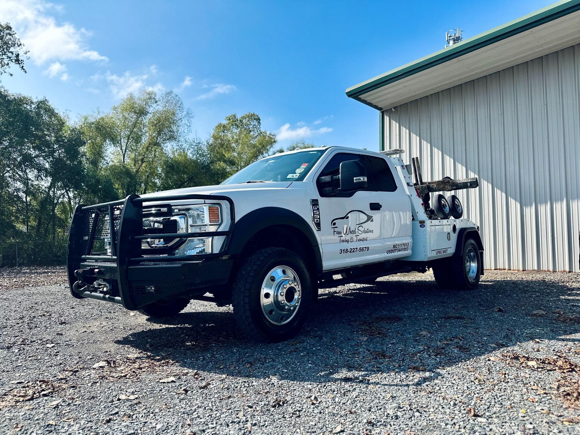 A white tow truck is parked in front of a building.
