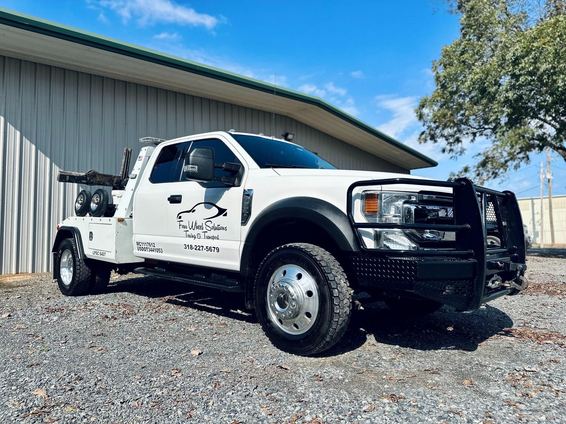 A white tow truck is parked in front of a building.