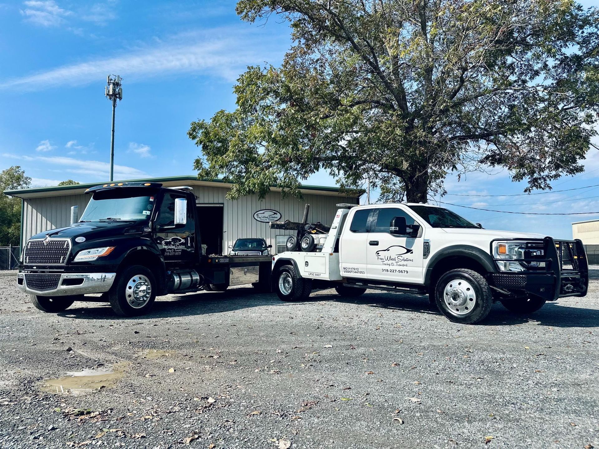 Two tow trucks are parked next to each other in a gravel lot.