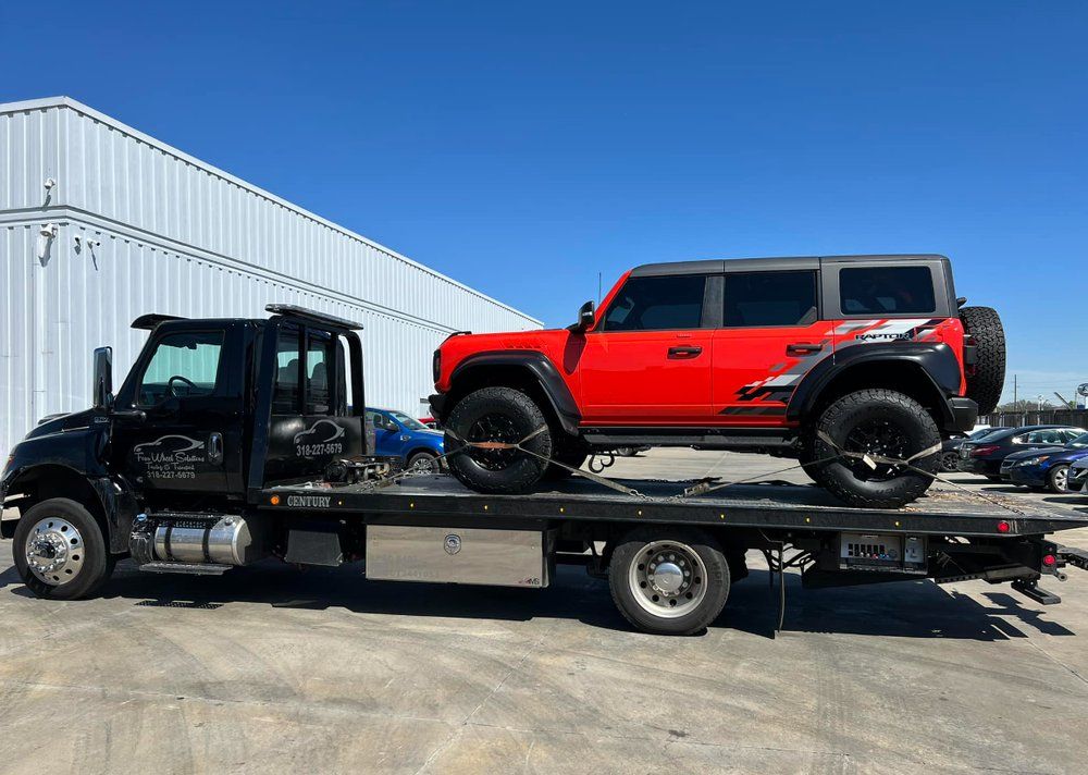 A red jeep is being towed by a tow truck.
