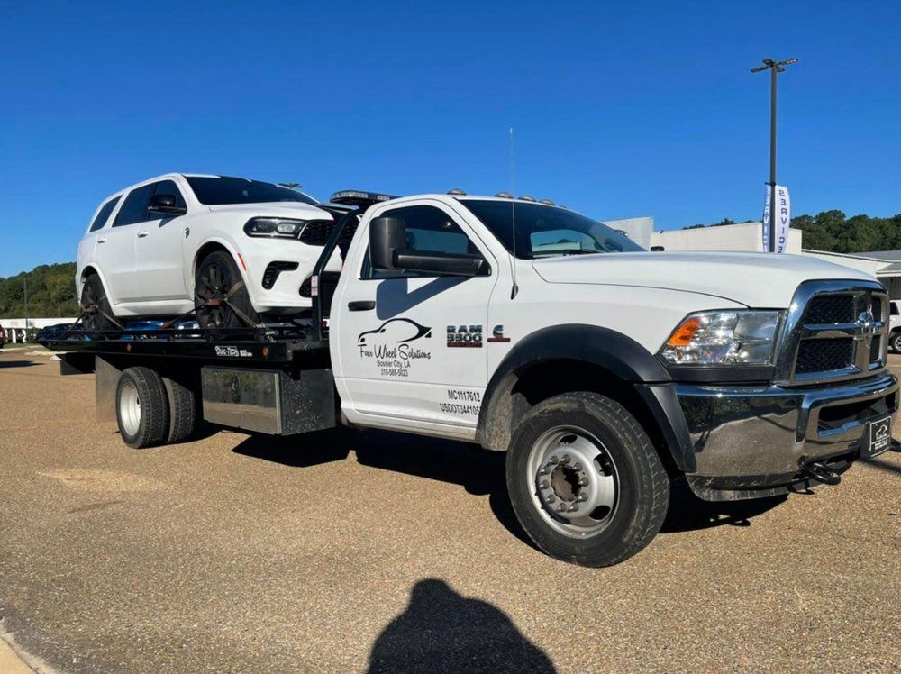 A white tow truck with a white car on the back of it.