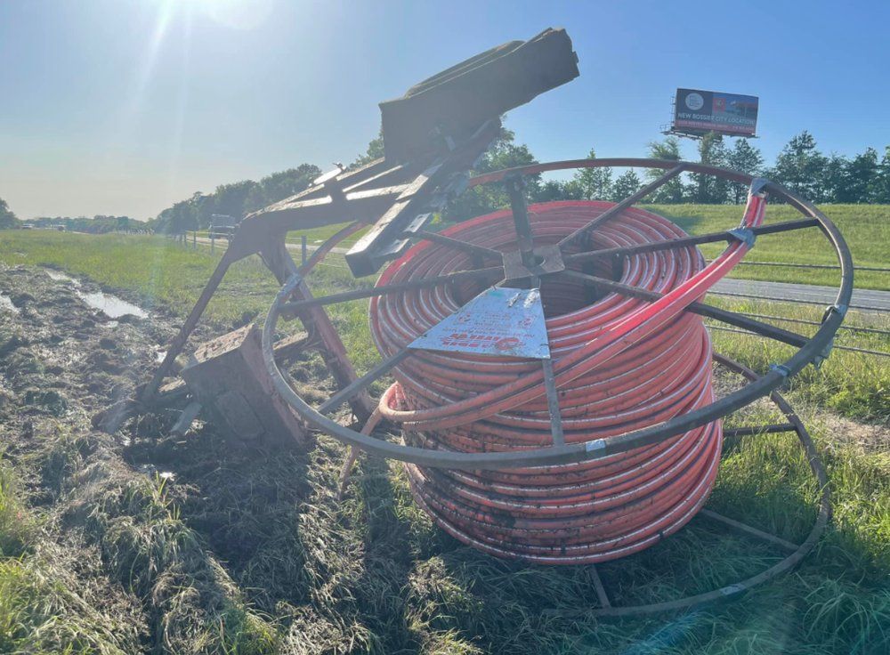 A large spool of orange hose is sitting in the middle of a field.