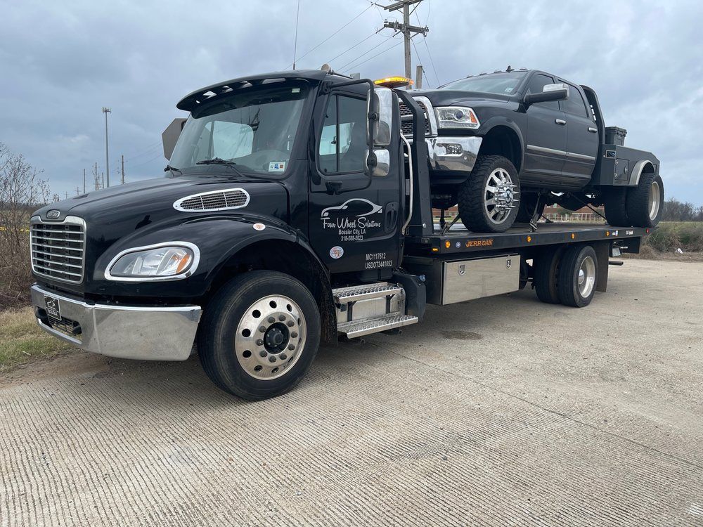 A black tow truck is towing a black truck.