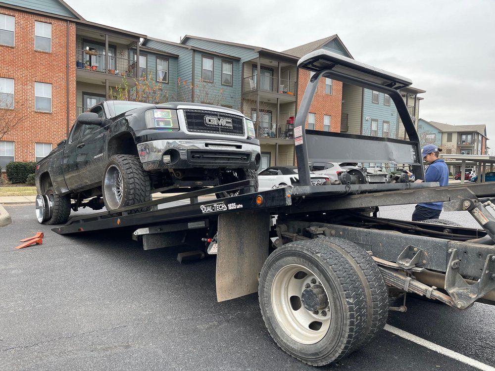 A gmc truck is being towed by a tow truck.