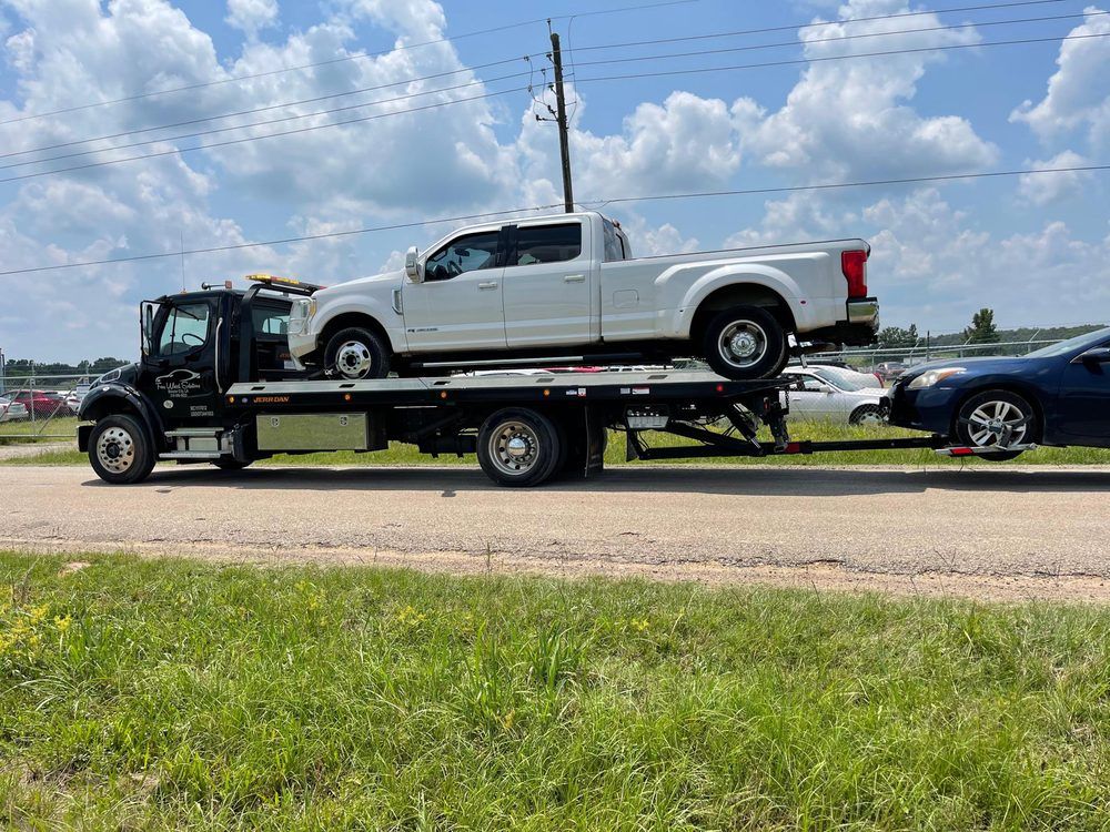 A white truck is being towed by a tow truck.
