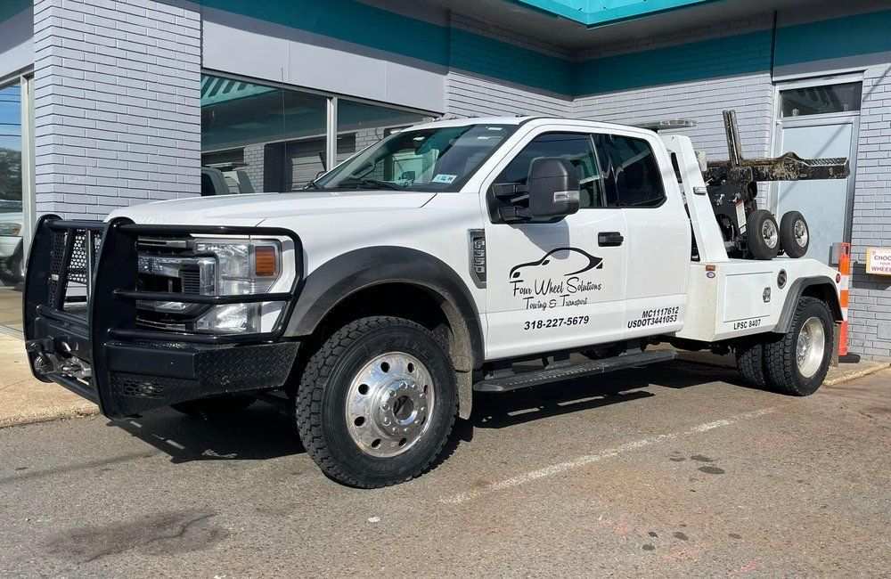 A white tow truck is parked in front of a building.