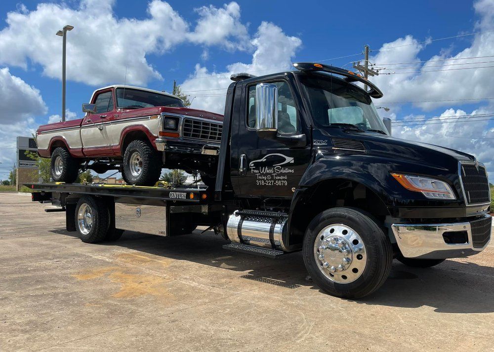 A tow truck is towing a red and white truck.