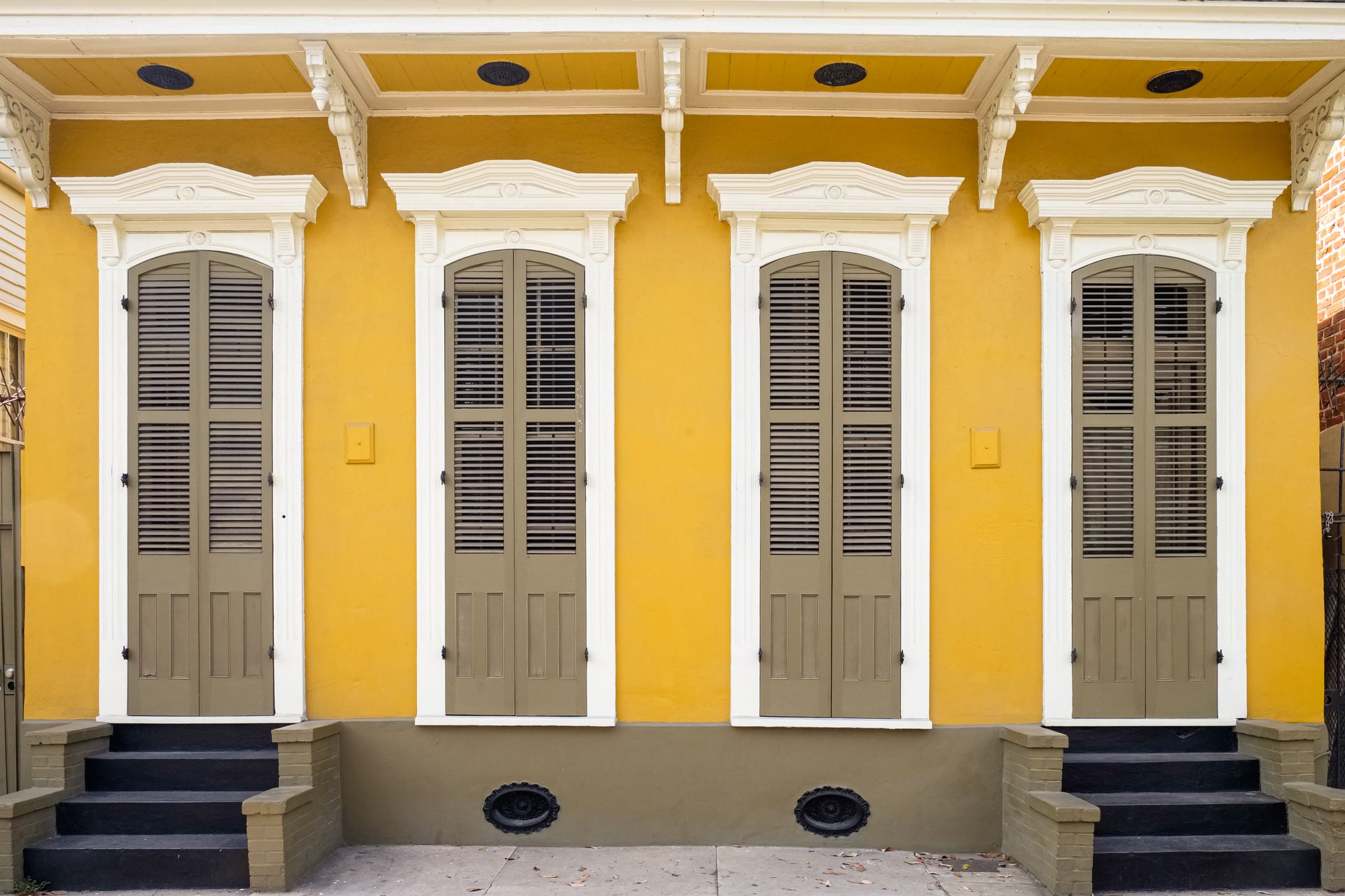 Yellow historic New Orleans home with shutters and decorative trim, classic New Orleans real estate