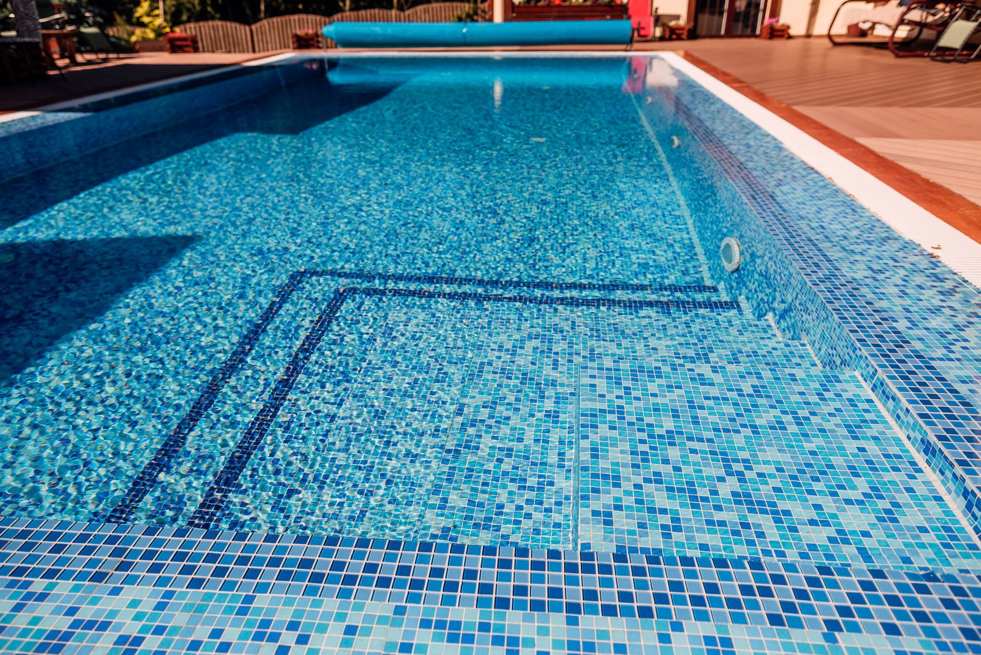 Blue tiled swimming pool with a rectangular shallow section and surrounding deck area