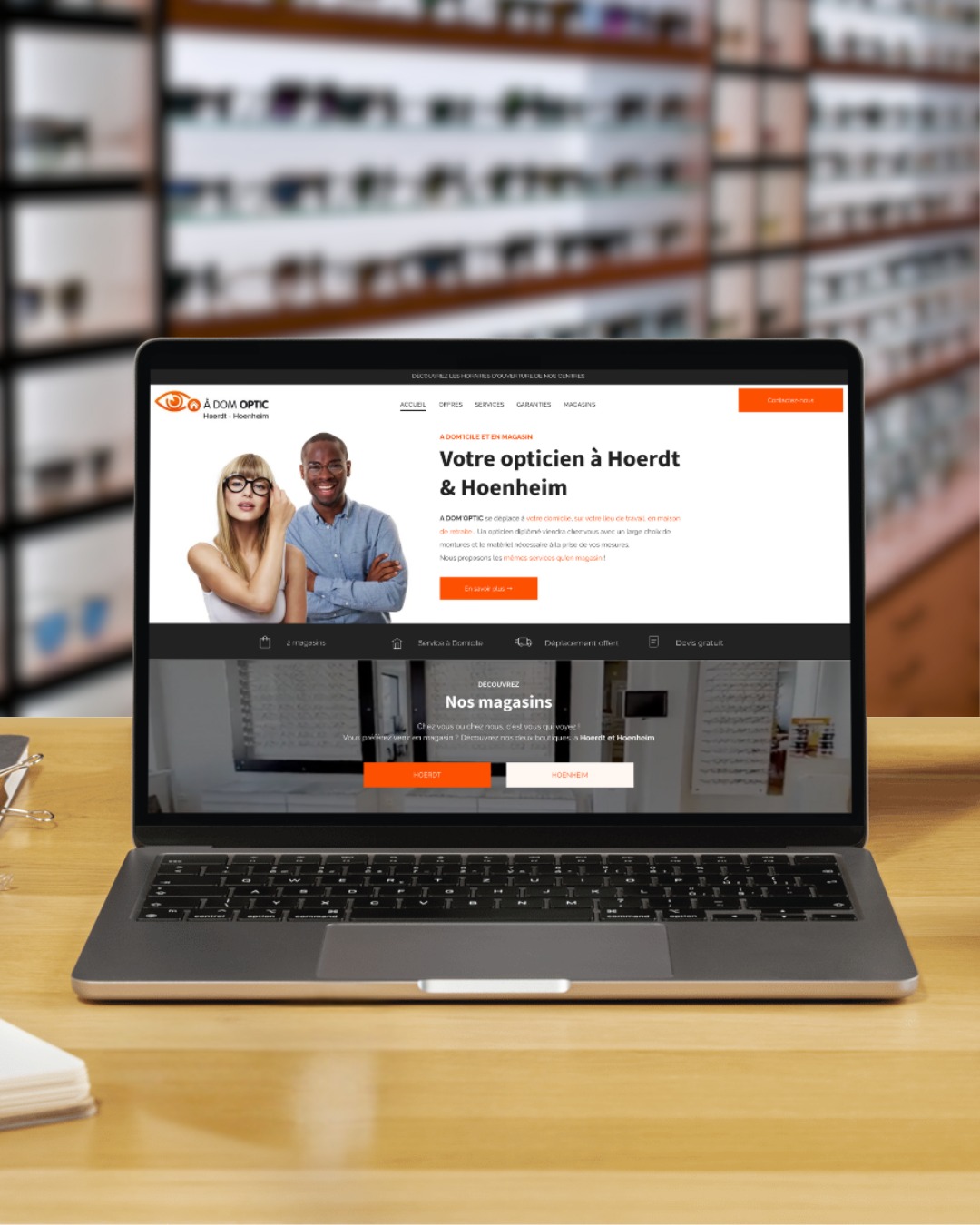 Ordinateur portable affichant le site Web d'un cabinet d'opticien, avec des étagères de lunettes en arrière-plan.