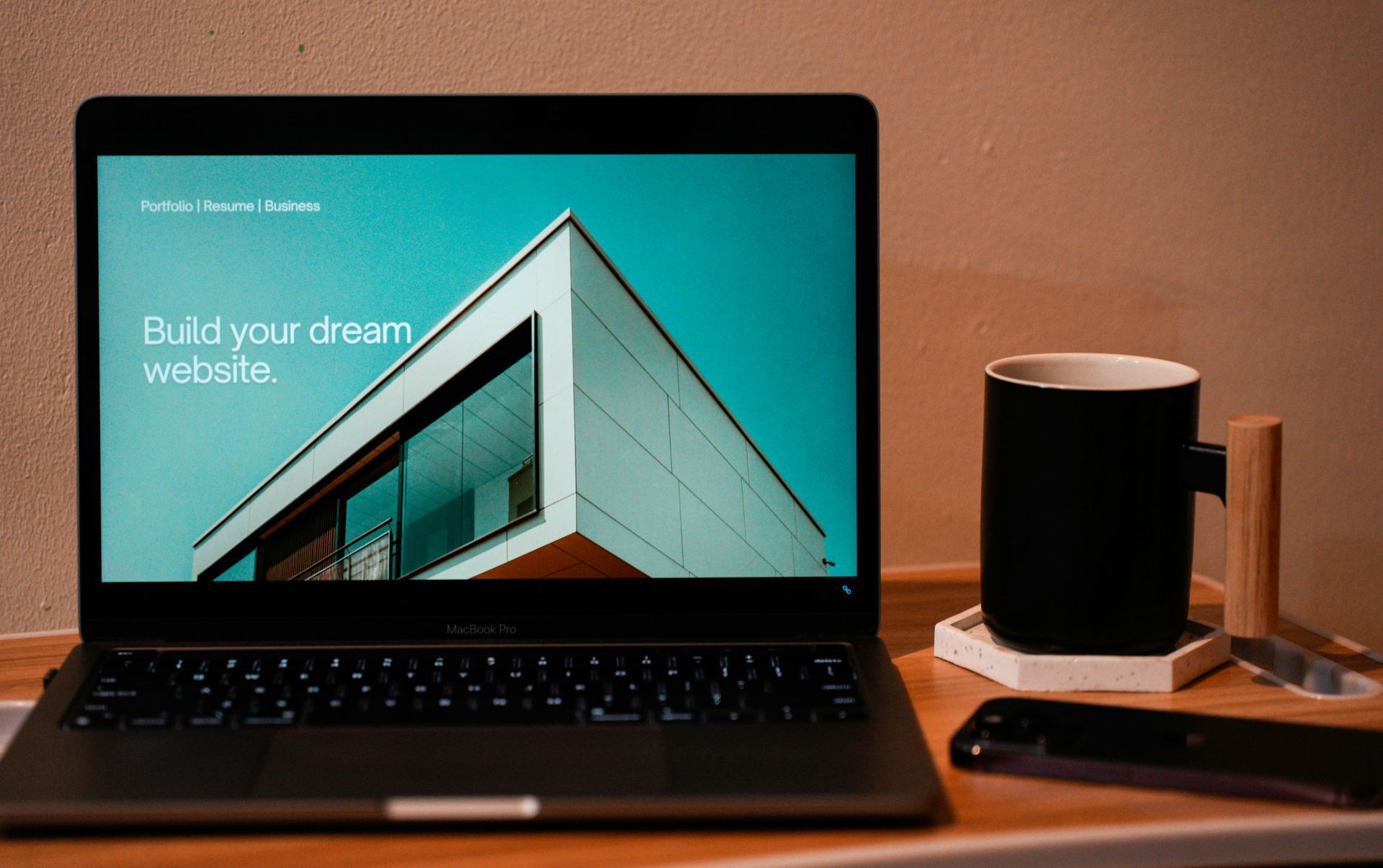 Ordinateur portable affichant un design architectural, une tasse noire sur un sous-verre et une télécommande.