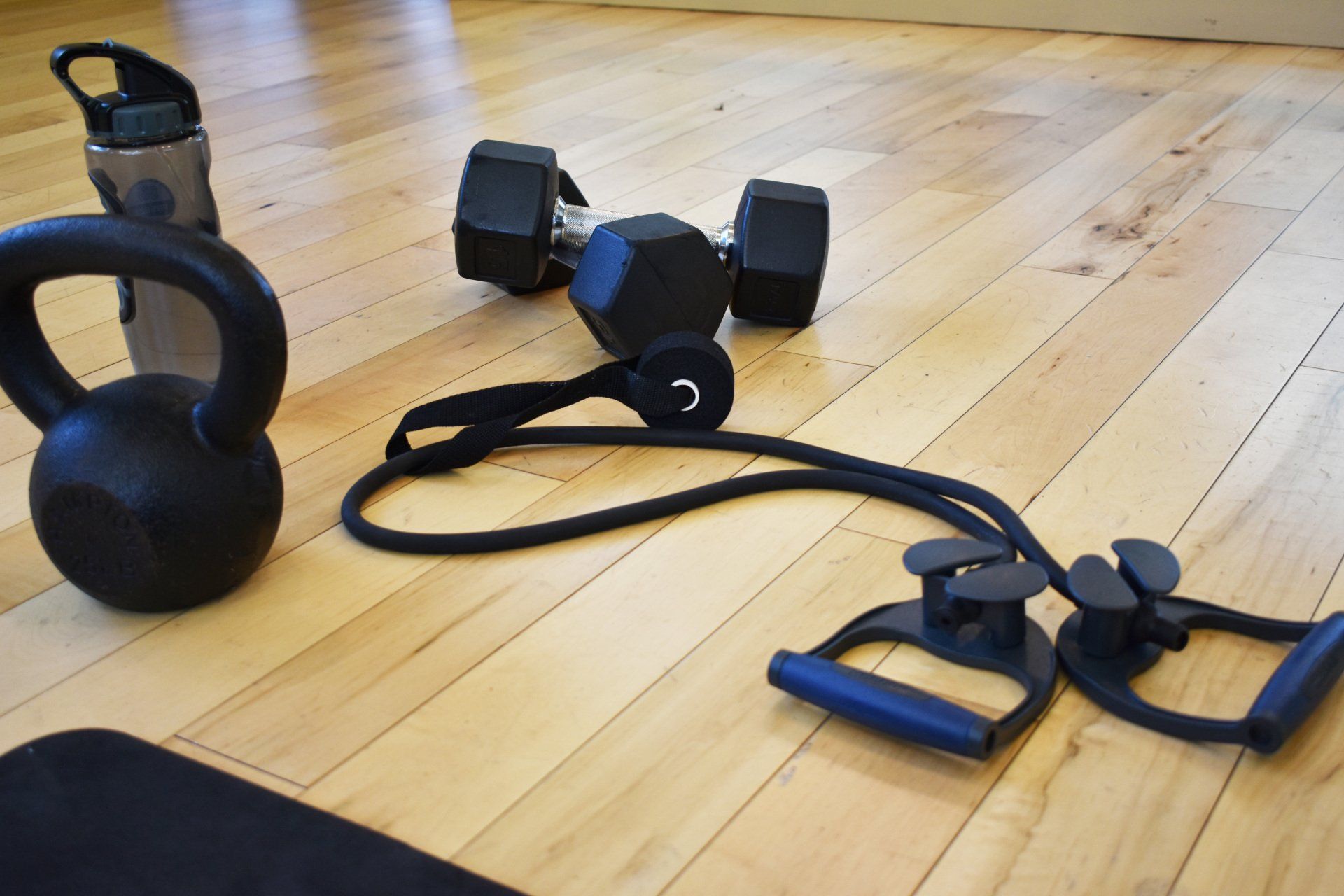 A Kennel ball, 2 Barbells, and a resistance band used for online personal training on the floor,