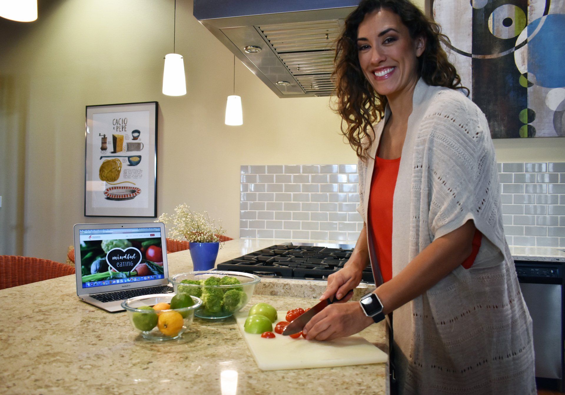 Nutrition personal trainer Alta wearing a red shirt cutting a tomato in a kitchen