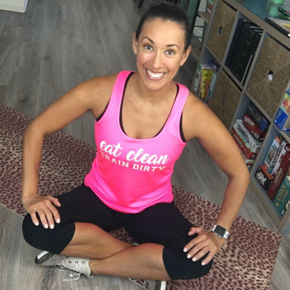 Fitness Coach Alta sitting on the floor cross legged, wearing a pink tank top that reads 