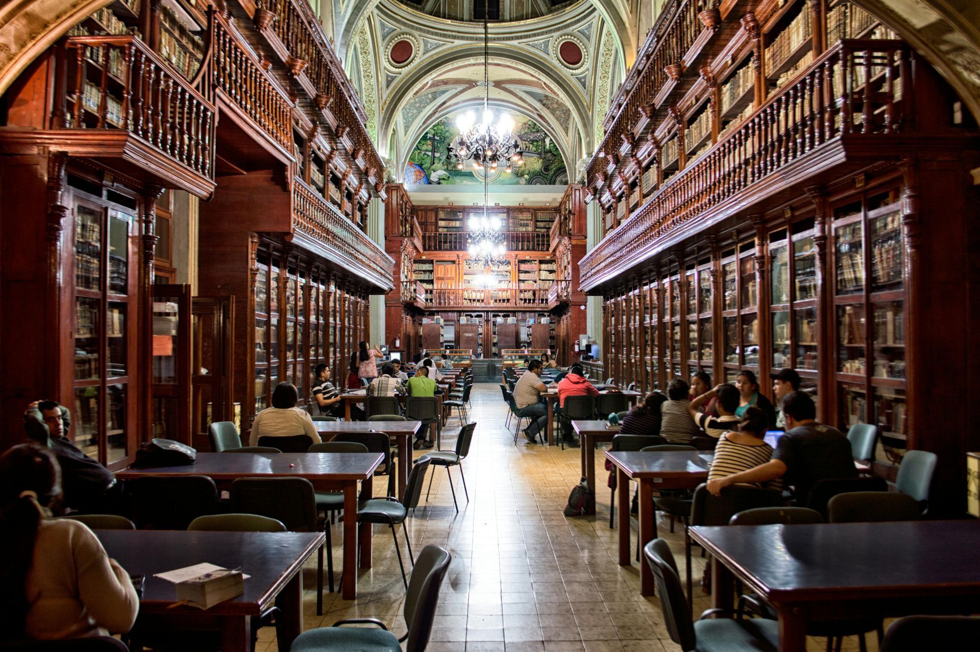A group of people are sitting at tables in a library.