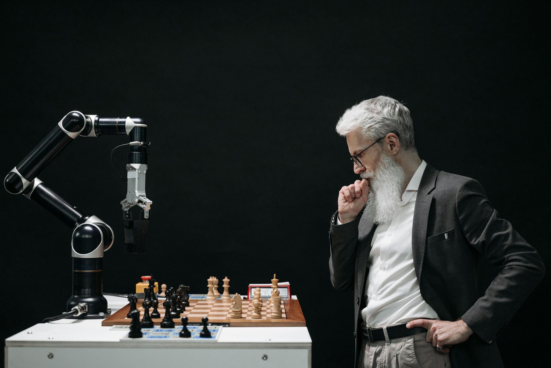 A man is playing chess with a robotic arm.