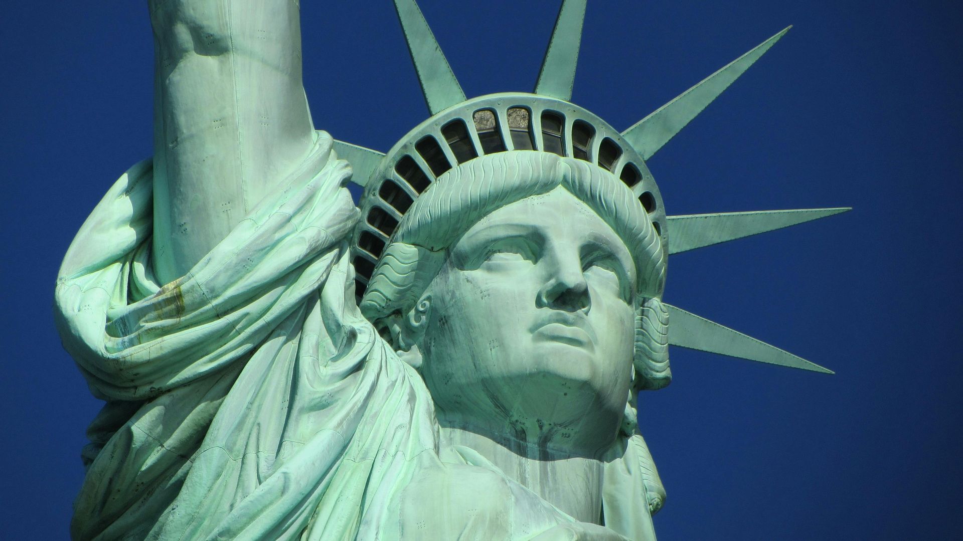 The statue of liberty is against a blue sky.
