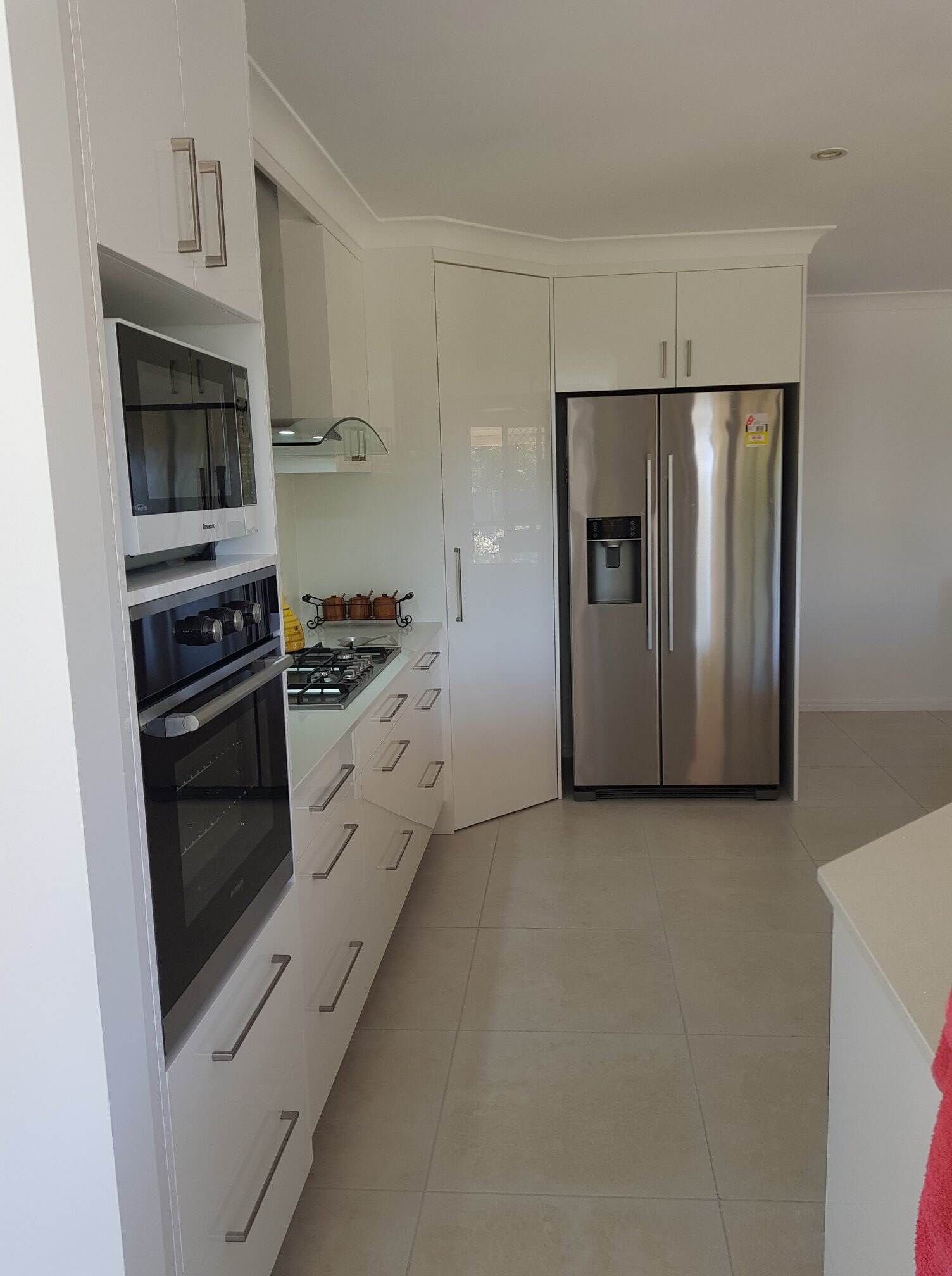 A Kitchen With White Cabinets and a Stainless Steel Refrigerator — Regalline Cabinets & Joinery in Svensson Heights, QLD