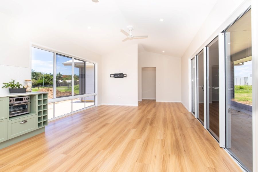 An empty living room with hardwood floors and lots of windows.